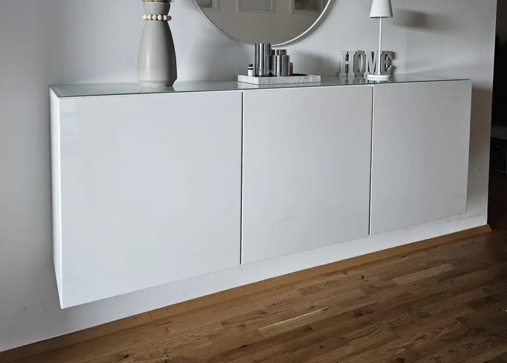 Weißer Hängeschrank an der Wand mit rundem Spiegel darüber