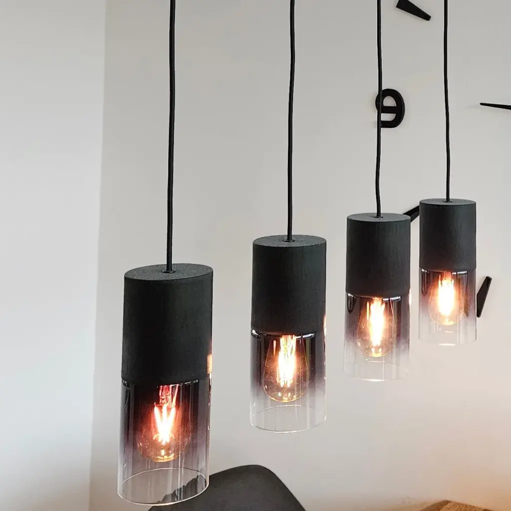 Vier Pendelleuchten mit Glasschirmen an einer Deckenschiene über einem Esstisch